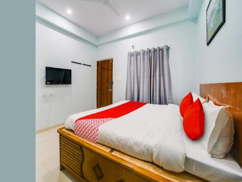 Hotel Olive Square في Shamsgarh: غرفة نوم بسرير ومخدات حمراء وبيضاء