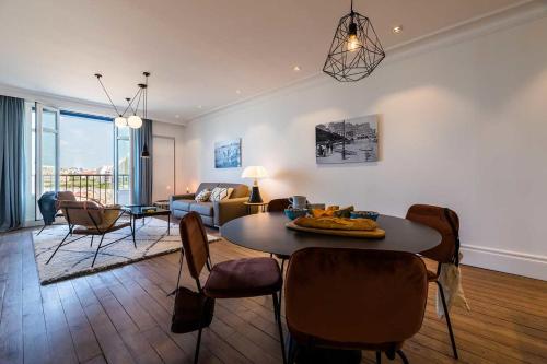 a living room with a table and chairs and a couch at BEACHVIEW KEYWEEK Beachfront Renovated Apartment with Parking in Biarritz in Biarritz