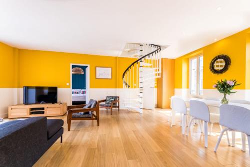 - un salon avec des murs jaunes, une table et des chaises dans l'établissement LES HALLES KEYWEEK Duplex with Terrace and Parking in Biarritz Center, à Biarritz
