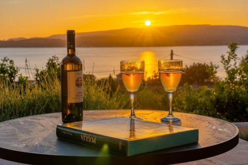 a bottle of wine and two glasses on a table with the sunset at THALASSA VIEW RESIDENCE in Argostoli