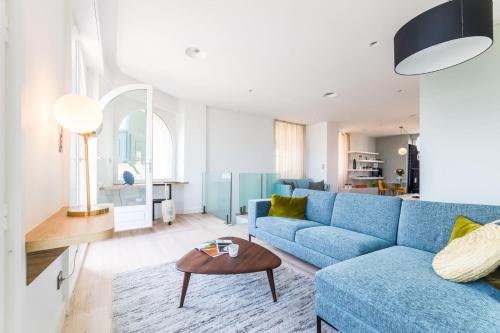 un salon avec un canapé bleu et une table dans l'établissement BALEA KEYWEEK Seafront Duplex Apartment with Balcony Garage in Biarritz, à Biarritz