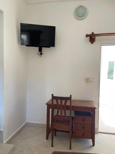 a wooden table with a chair and a television on a wall at HOTEL AKBAR in Mahajanga