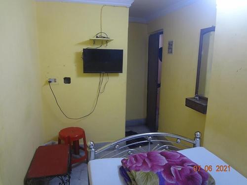 um quarto com uma mesa e uma televisão na parede em Khaja Hotel em Calcutá