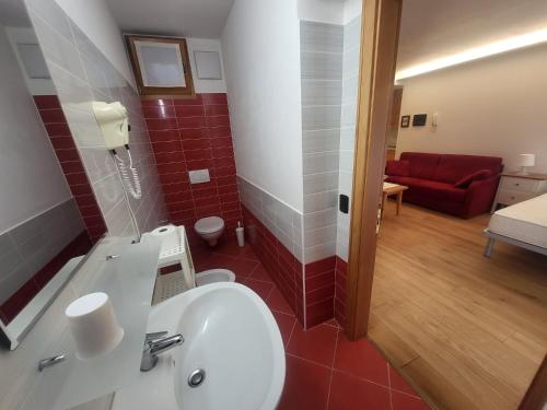 a bathroom with a sink and a red couch in a room at monolocale Ambrosi in Pinzolo