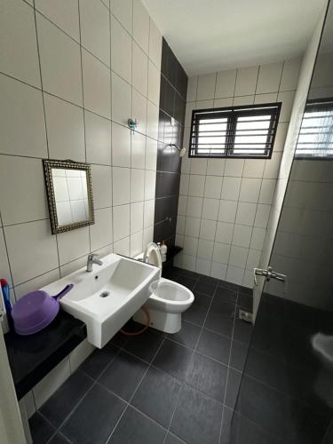 Un baño con un lavabo blanco y un inodoro. en Dhuha Homestay, en Kampong Kerubong