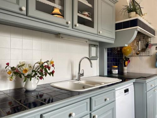 - une cuisine avec un évier et un vase de fleurs dans l'établissement 758 - Charmante maison en pierre, à quelques minutes des plages du Guen et du centre d'Erquy, à Erquy