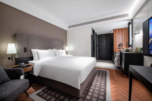 a bedroom with a large white bed and a living room at Intercity Wuhan Guanshan Avenue in Wuhan