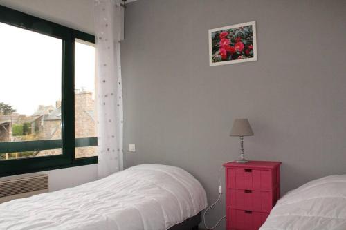 - une chambre avec deux lits et une commode rouge avec une fenêtre dans l'établissement 525 - A ERQUY, dans cet immeuble, situé à 300m du centre et 200m de la plage, à Erquy