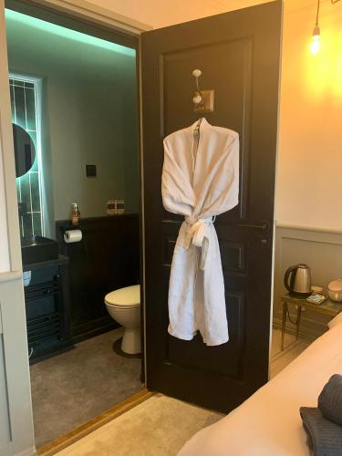 La salle de bains est pourvue de toilettes et d'un peignoir suspendu à une porte. dans l'établissement Petit Boudoir The Riverside Retreat, à Triac-Lautrait