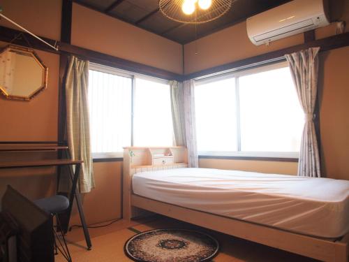 a bedroom with a bed and two large windows at Classy Busshozan - Vacation STAY 15858 in Takamatsu