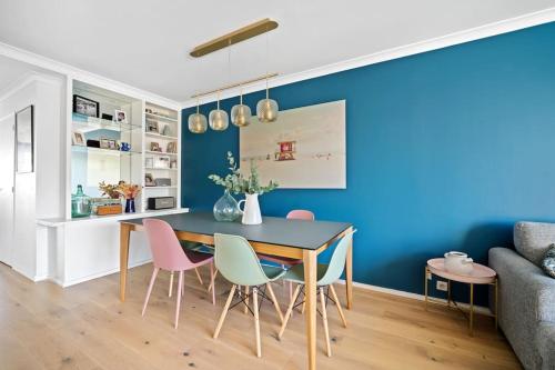 une salle à manger avec un mur bleu, une table et des chaises dans l'établissement Spacious duplex with terraces, à Boulogne-Billancourt