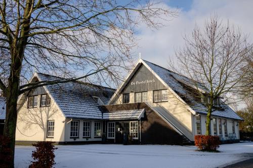 ein weißes Gebäude mit einem schwarzen Dach im Schnee in der Unterkunft De Postelhoek B&B in Oud-Ootmarsum