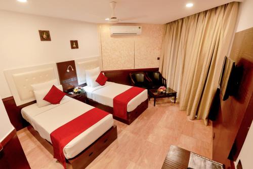 a hotel room with two beds and a chair at Renai Blue Waters Cherai in Cherai Beach