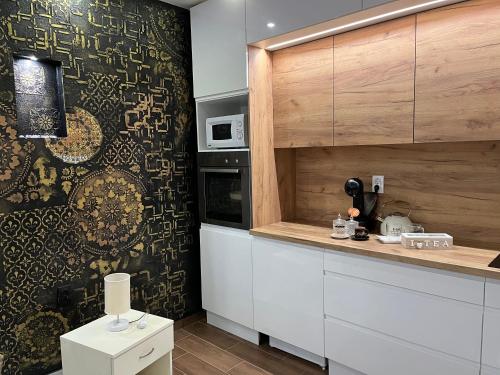 a kitchen with white cabinets and a patterned wall at Apartman Delux in Bačka Topola