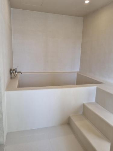 a white bathroom with stairs and a faucet at Island Stay in Jeju