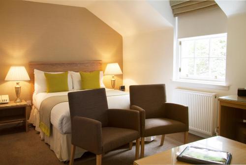 a hotel room with a bed and two chairs at Royal Scots Club in Edinburgh