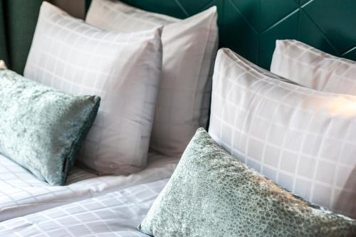 a bed with white pillows and green and white pillows at Apartments By Ligula, Hammarby Sjöstad in Stockholm