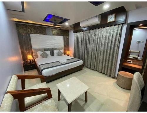 a bedroom with a bed and a living room at Pearl Heights Hotel, Malda, WB in Māldah