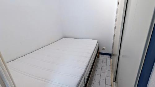 - un petit lit blanc dans une petite chambre dans l'établissement 5017 Tennis Village 602, au Cap d'Agde