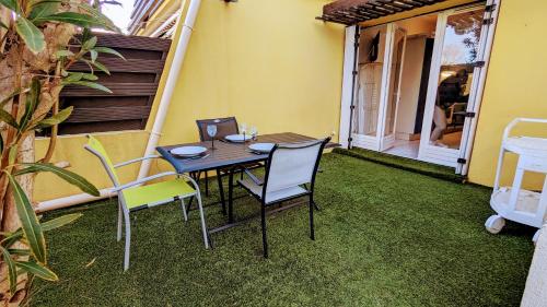 une table et des chaises sur une terrasse avec pelouse dans l'établissement 5017 Tennis Village 602, au Cap d'Agde