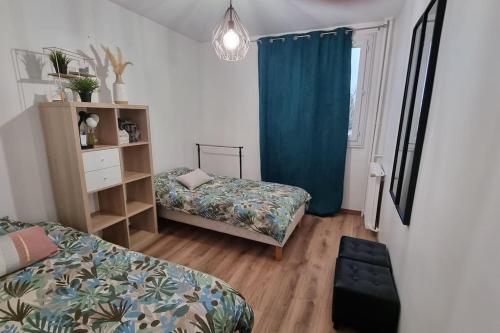 Habitación con 2 camas y cortina azul en Logement spacieux rénové, calme et proche du métro en Villeurbanne