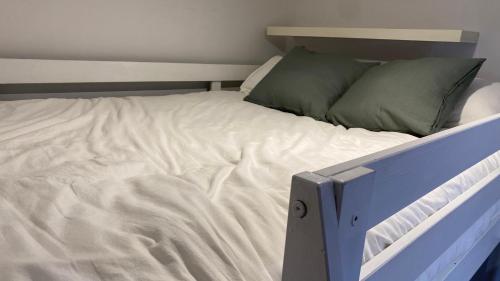 Una cama con sábanas blancas y almohadas verdes. en Apartamento en el casco antiguo, en Madrid