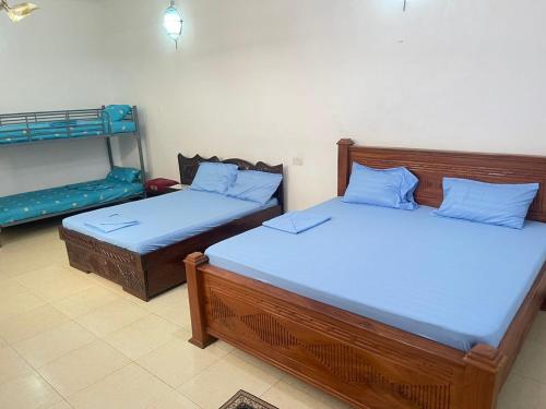 two beds with blue pillows in a room at Mystic Manor Stonetown B&B in Stone Town