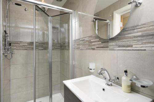 een badkamer met een douche, een wastafel en een spiegel bij Church House Inn, Stokenham in Kingsbridge