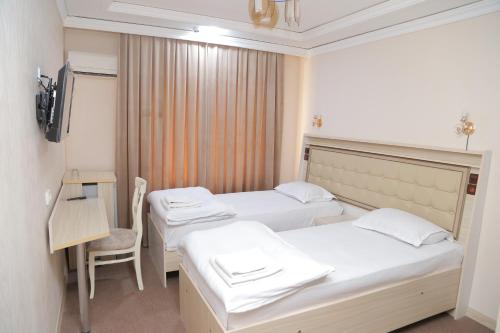 una habitación de hospital con 2 camas y una silla en URGANCH HOTEL, en Urganch