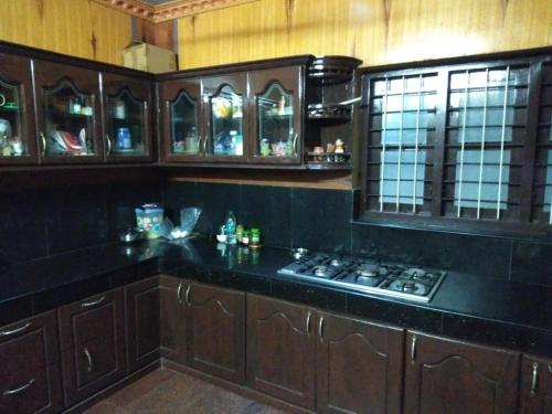 a kitchen with wooden cabinets and a stove in it at MN Homestay in Varkala