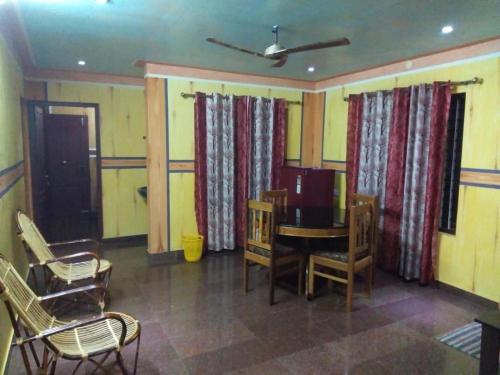 Cette chambre comprend une table, des chaises et des rideaux. dans l'établissement MN Homestay, à Varkala