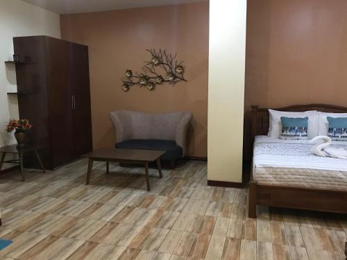 a bedroom with a bed and a chair and a table at Charos Dormitel in Dumaguete