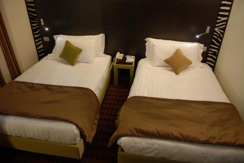 カーゼ・ヌオーヴェにあるファースト ホテル マルペンサのベッド2台とテーブルが備わるホテルルームです。