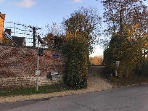 a brick wall with a hedge on the side of a street at La Cense - Mélin in Jodoigne