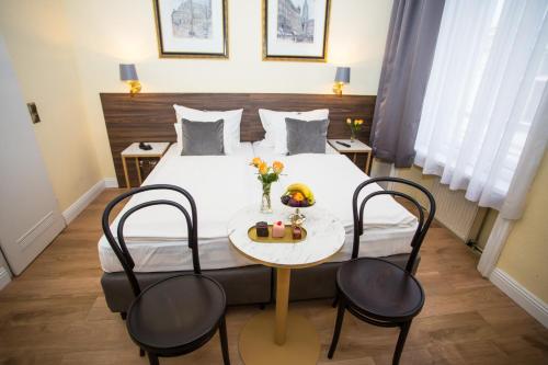 ウィーンにあるCity Pension Stephansplatz I Self Check Inのベッド1台、テーブル、椅子が備わるホテルルームです。