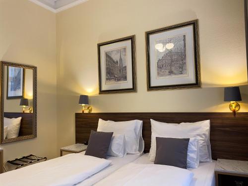 a bedroom with two beds and two pictures on the wall at City Pension Stephansplatz I Self Check In in Vienna