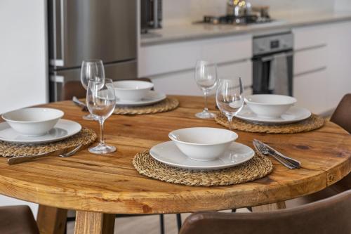 a wooden table with plates and wine glasses on it at Welgelegen 608 by Host Agents in Strand