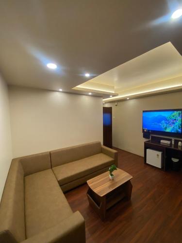 a living room with a couch and a flat screen tv at XCELSIOR HOTEL & SPA in Shillong