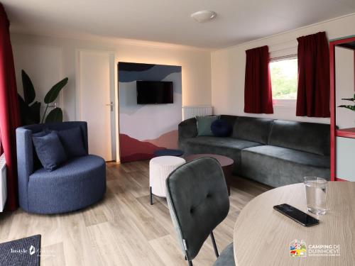 a living room with a couch and a table at Camping de Duinhoeve Chalet Bosdier not for companies in Burgh Haamstede
