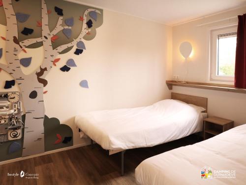 a bedroom with two beds and a tree mural at Camping de Duinhoeve Chalet Bosdier not for companies in Burgh Haamstede