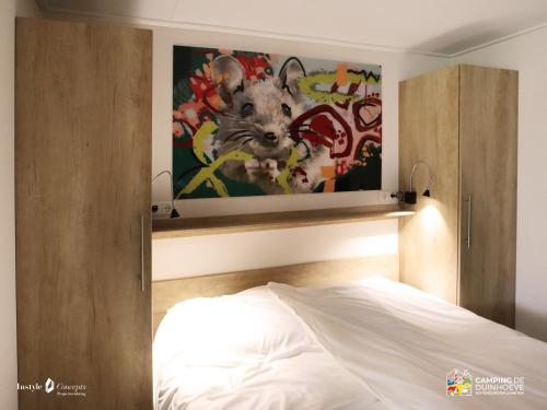 a bedroom with a bed and a painting of a mouse at Camping de Duinhoeve Chalet Bosdier not for companies in Burgh Haamstede