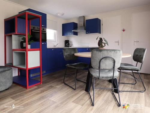 a kitchen with blue cabinets and a table and chairs at Camping de Duinhoeve Chalet Bosdier not for companies in Burgh Haamstede