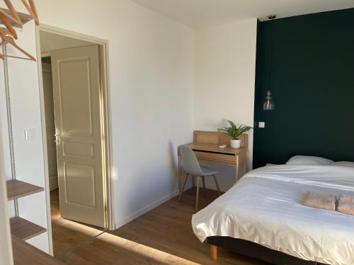 a bedroom with a bed with a green headboard and a desk at Appart-Hôtel Résidence de Garonne in Tonneins