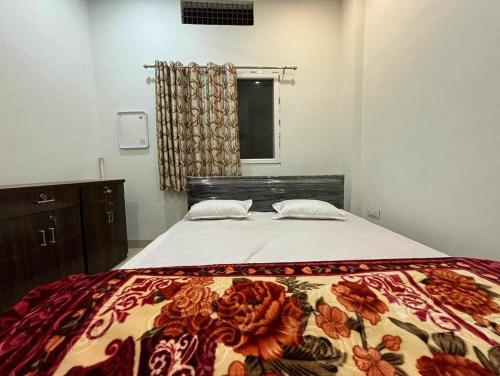 a bedroom with a bed with a flowered blanket on it at Madhuri Guest House in Varanasi