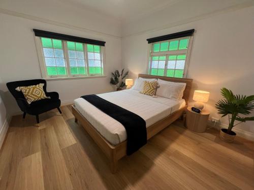 a bedroom with a bed and a chair and two windows at Sans Souci Apartments in Ingham