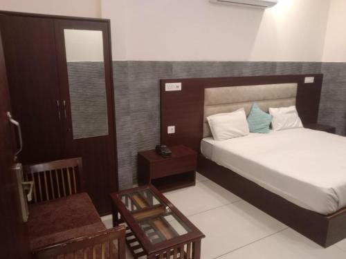 een slaapkamer met een bed, een spiegel en een tafel bij Hotel Park Green in Pānīpat