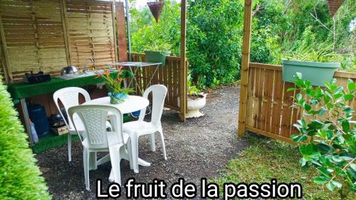 a patio with a table and chairs in a garden at CAMPING le fruit de la passion in Saint-Louis