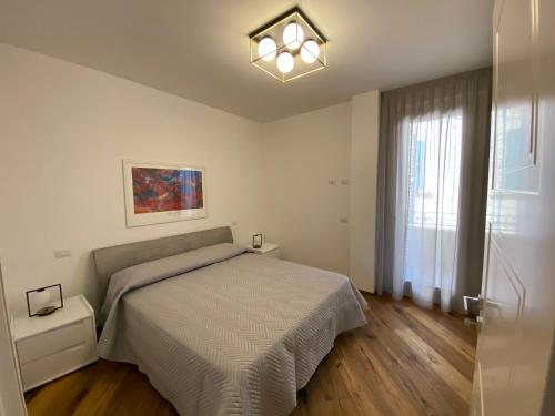 a white bedroom with a bed and a window at Charming Apts - Via Pastrengo in Porto Recanati