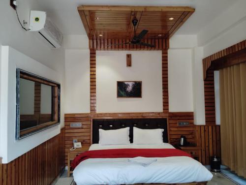a bedroom with a large bed with a wooden headboard at Hotel CM Palace - Pure Vegetarian 
