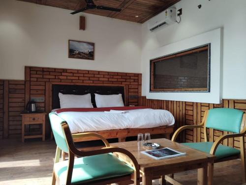 a bedroom with a bed and a table and chairs at Hotel CM Palace - Pure Vegetarian in Ner Chowk
